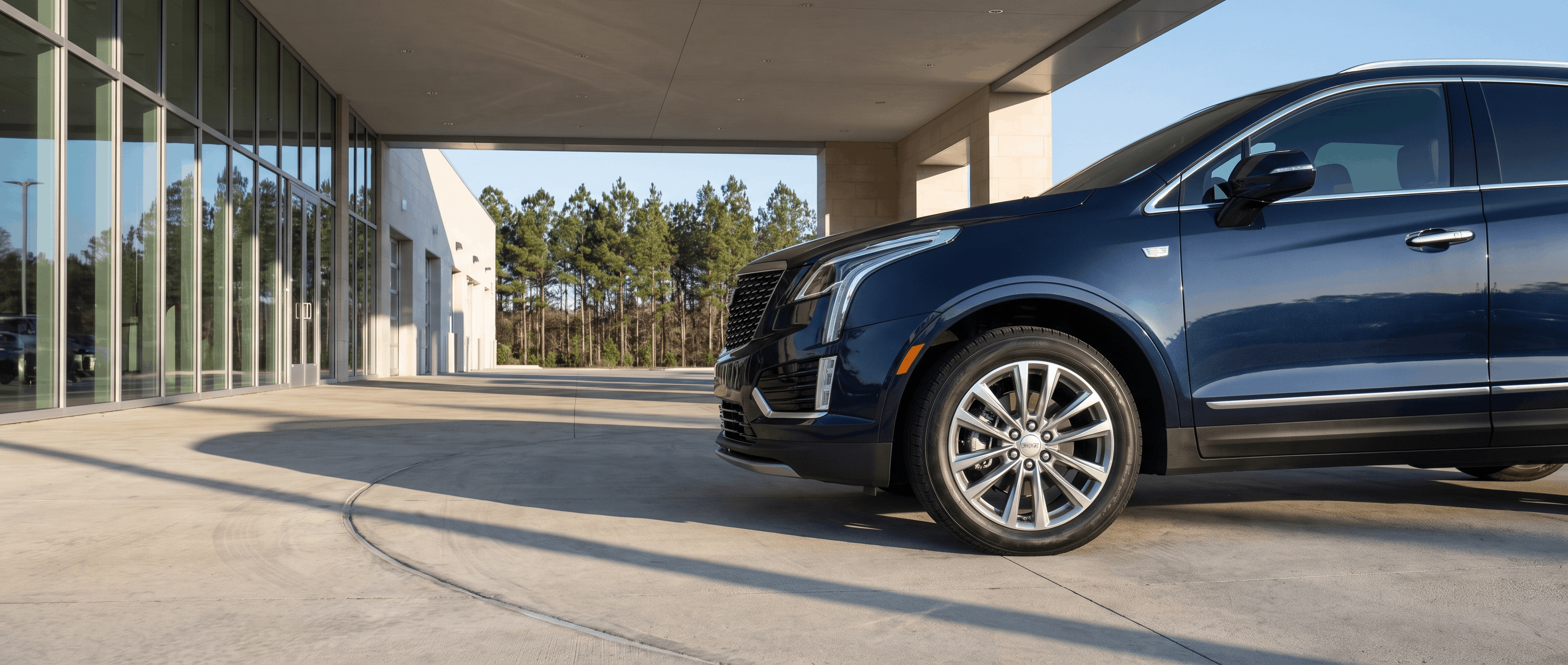 2026 Cadillac CT5 and XT5 parked together at dusk near a Mississippi pine treeline